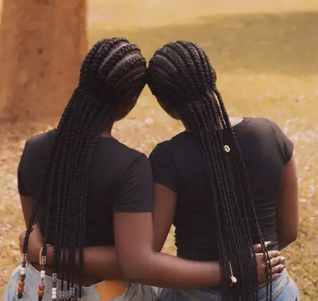 Duas amigas de costas, com tranças compridas e missangas nas pontas