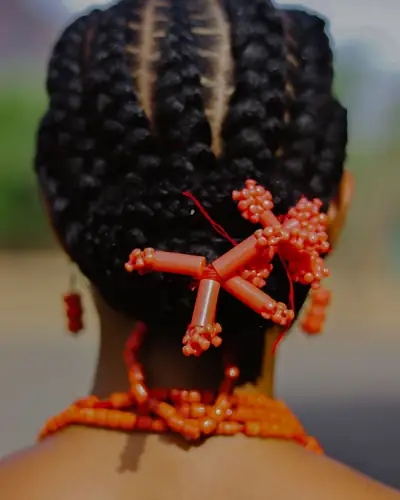 Penteado de tranças apanhado atrás, com missangas cor de laranja